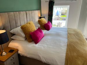 a bed with pink pillows on it with a window at Willow Mews in Swansea