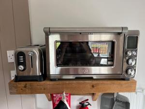 a toaster oven sitting on a wooden shelf with a toaster at Willow Mews in Swansea