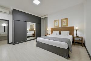 1 dormitorio con 1 cama grande y espejo grande en Garden Hotel, en Ribeirão Preto