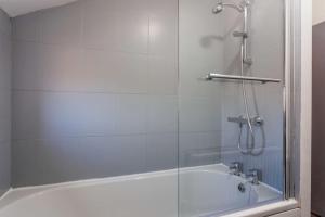a shower with a glass door next to a bath tub at Guest Homes - Bambro Apartment in Sunderland