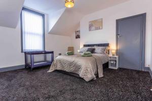 a bedroom with a bed and a table and a window at Guest Homes - Bambro Apartment in Sunderland