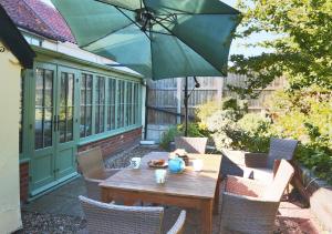 The Cottage في Scole: طاولة وكراسي خشبية مع مظلة على الفناء