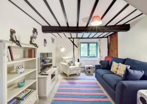 sala de estar con sofá azul y TV en The Cottage en Scole