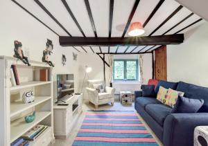 a living room with a blue couch and a tv at The Cottage in Scole