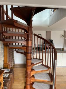 a wooden spiral staircase in a living room at Willow Mews in Swansea