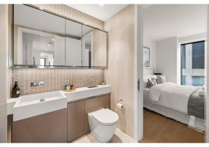 a bathroom with a sink and a toilet and a bed at Elegant and Modern Apartments in Canary Wharf right next to Thames in London