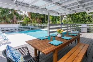 einen Holztisch und Stühle auf einer Terrasse mit einem Pool in der Unterkunft Luxury Villa 5BR and 3BR in Hollywood Lakes near Beach in Hollywood