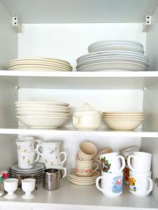 un estante lleno de platos y tazas en Sirenetta, en De Haan