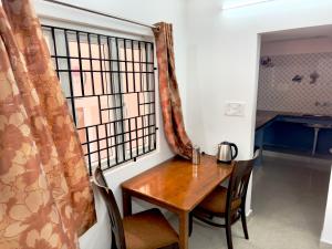 a table and chairs in a room with a window at Sishya Service Apartment- 1bhk, IT Expressway, Thoraipakkam, OMR, chennai in Chennai