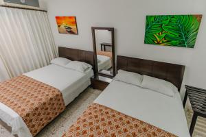 a hotel room with two beds and a mirror at Casa Hotel Miriam in Montería
