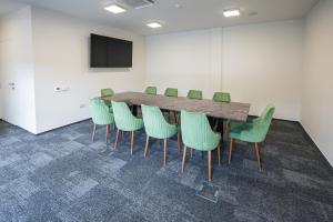 uma sala de conferências com uma mesa de madeira e cadeiras verdes em ALIVE HOTEL em Oradea