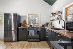 eine Küche mit schwarzen Schränken und Edelstahlgeräten in der Unterkunft Hudson Valley and The Berkshires Cottage in Hillsdale