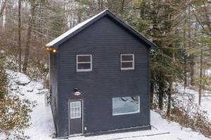 ein schwarzes Haus mit einer Tür im Schnee in der Unterkunft Hudson Valley and The Berkshires Cottage in Hillsdale