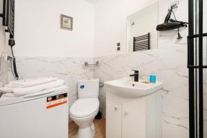 biała łazienka z toaletą i umywalką w obiekcie Nawrot Cosy Studio w Łodzi
