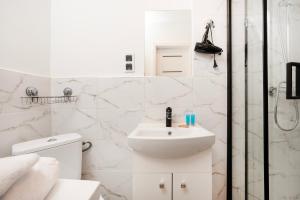 biała łazienka z umywalką i prysznicem w obiekcie Nawrot Cosy Studio w Łodzi