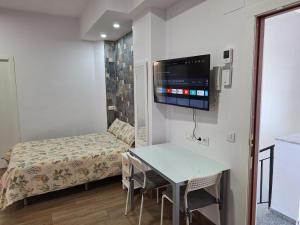 Habitación pequeña con mesa, cama y TV. en TourismCasa, en Dos Hermanas