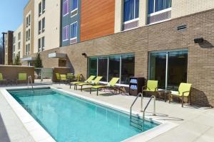 a swimming pool with chairs and tables next to a building at SpringHill Suites by Marriott Arlington TN in Arlington