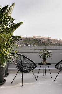 Un balcón con 2 sillas y una mesa con plantas. en Regal Hotel Mitropoleos, en Atenas