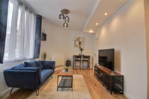 a living room with a blue couch and a television at Le Cocon De Pleyel in Saint-Denis +6 photos