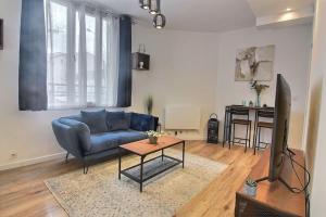a living room with a blue couch and a table at Le Cocon De Pleyel in Saint-Denis