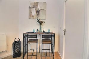 a small table with two chairs and a vase on it at Le Cocon De Pleyel in Saint-Denis