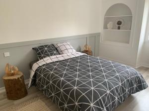 Schlafzimmer mit einem Bett mit einer schwarzen und weißen Bettdecke in der Unterkunft La maison du lavoir in Fain-lès-Montbard