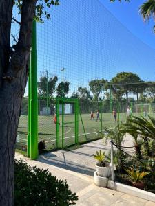 a green tennis court with people playing on it at Villaggio Mondial Camping in Metaponto