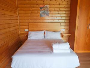 un letto con lenzuola e cuscini bianchi in una stanza di Villas turísticas del noroeste a Villanueva de Arosa