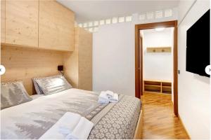 a small bedroom with a bed and a flat screen tv at La Casetta Vintage - In centro con box auto privato in Bormio