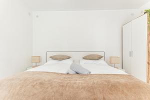 um quarto branco com uma cama grande e 2 candeeiros em City Vibes: 1BR Apt, 10 Min to Westbahnhof em Viena