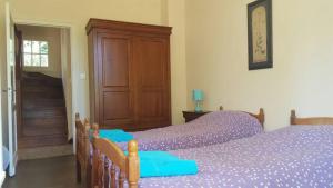 a bedroom with two beds with purple sheets and a wooden door at Le Chalet du Moulin Blanc in Bergerac