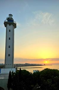 a lighthouse with the sunset in the background at Sea View Luxury 1-bd Apartment Marina Cape Aheloy in Aheloy