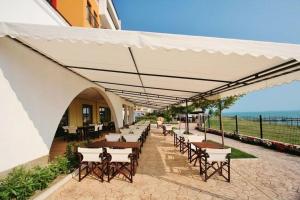 a patio with tables and chairs under a white umbrella at Sea View Luxury 1-bd Apartment Marina Cape Aheloy in Aheloy