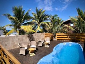 a deck with chairs and a swimming pool and palm trees at Grand Appartement - Pétrel 2 in Trois Bassins