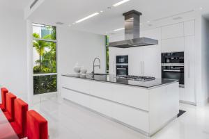 uma cozinha branca com um balcão e cadeiras vermelhas em Indulge in Waterfront Elegance Your Ultra Luxury Miami Beach Estate Beckons! em Miami
