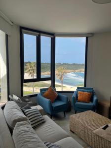 ein Wohnzimmer mit einem Sofa und Stühlen sowie einem Strand in der Unterkunft La Duna Son Parc - Apartamento in Son Parc