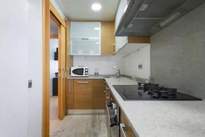 a kitchen with a stove and a microwave at Apartamento Playa con Piscina, Parking y 2 habitac in Castelldefels