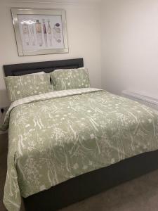 sypialnia z łóżkiem z zieloną kołdrą i poduszkami w obiekcie 2Philipot w mieście Eltham