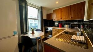 a kitchen with a sink and a table in it at Cosy flat Fulham Broadway in London