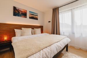 um quarto com uma cama grande e uma janela em Albert Residence Grand Chalet & SPA Poiana Brașov em Poiana Brasov