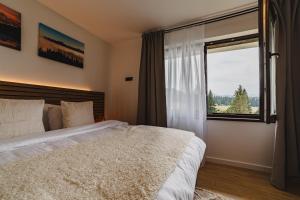 um quarto com uma cama grande e uma janela em Albert Residence Grand Chalet & SPA Poiana Brașov em Poiana Brasov