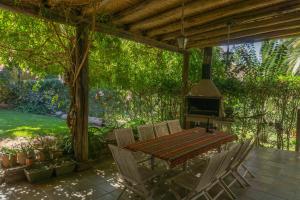 a wooden table and chairs on a patio with a stove at Ruca Luma B&B - Chacras in Ciudad Lujan de Cuyo