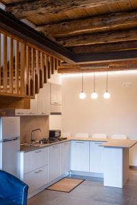 a kitchen with white cabinets and wooden ceilings at La Casa del Ciliegio in Feltre