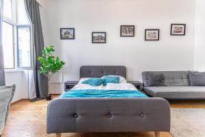 Bett mit blauen Kissen in einem Zimmer mit Sofa in der Unterkunft Stylish 1BR Apartment- Near Westbahnhof U3&U6 in Wien