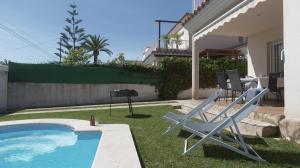 a pair of lawn chairs sitting next to a swimming pool at Casa Mar con piscina privada AA y Wi-Fi delante del mar. in Vinaròs