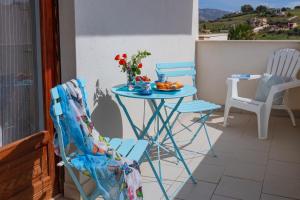 a blue table and chairs on a balcony with flowers at A'Mari - Holiday Home - Sciacca - 100mt dalla spiaggia Foggia - 100 meters from the beach in Sciacca