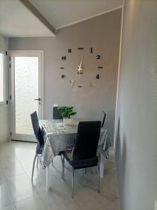 tavolo da pranzo con sedie e orologio sul muro di Appartamento Solemare a San Vito