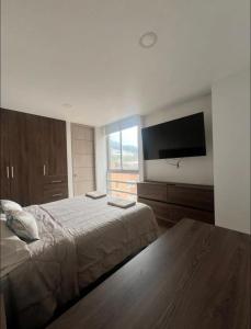 een slaapkamer met een bed en een flatscreen-tv bij Loft en Monserrate in Bogota