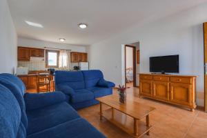 un soggiorno con divani blu e TV di APARTAMENTOS FLOR a Caleta de Sebo