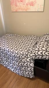 a bed with a black and white comforter in a bedroom at Small Cozy Room in Calgary